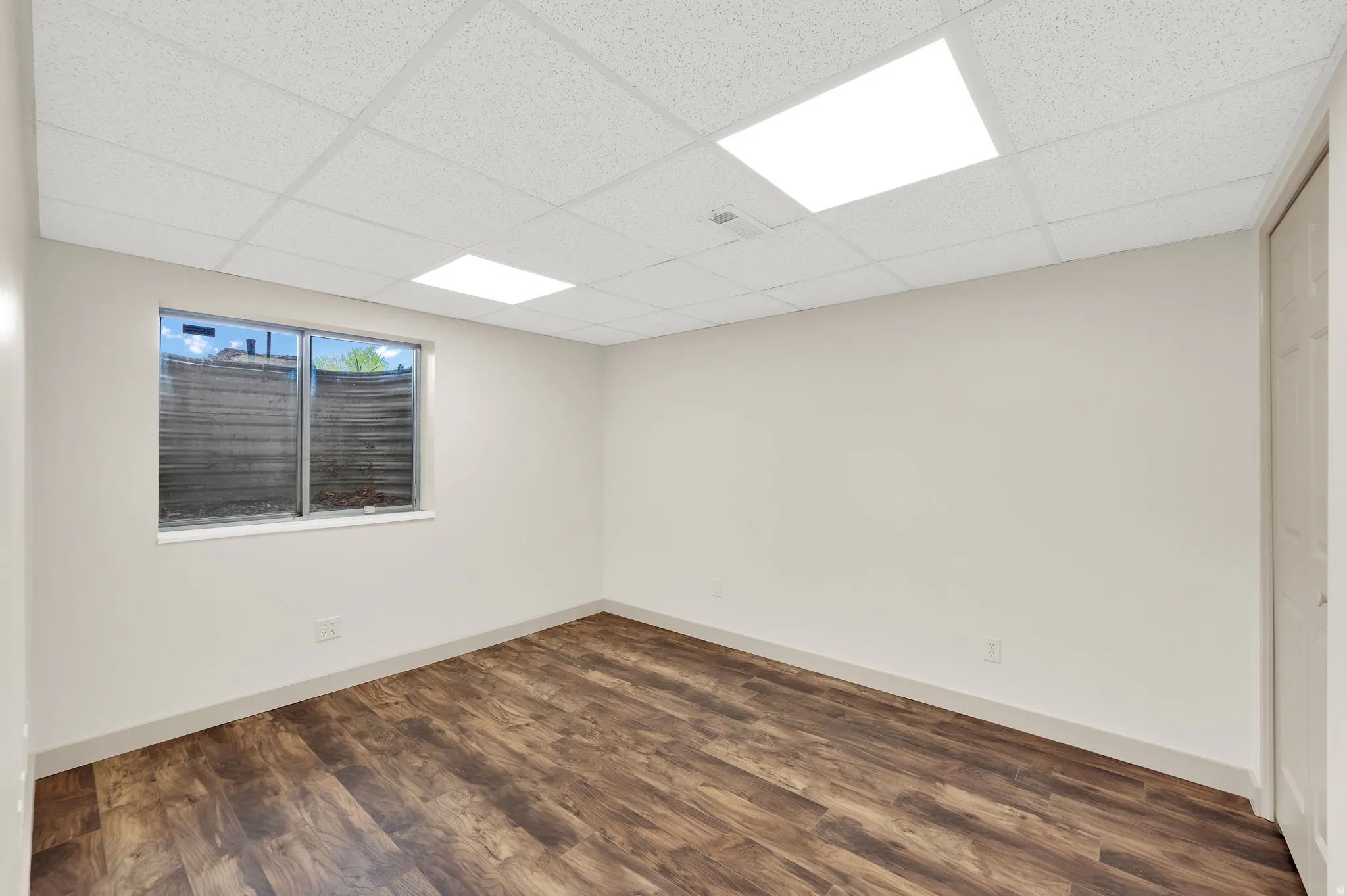 Spare room with dark wood finished floors and a drop ceiling