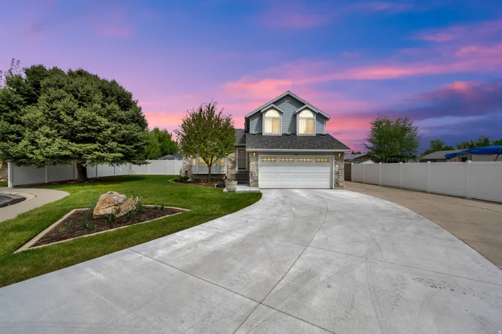 Traditional-style house with driveway, stone siding, and an attached garage
