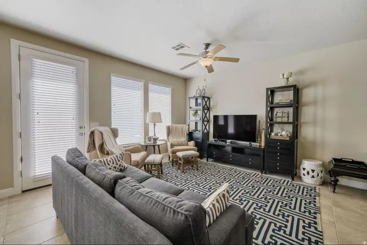 Living area featuring light tile patterned floors and ceiling fan