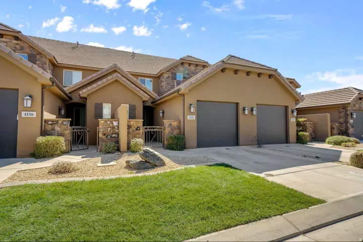 View of front of property with a gate, stucco siding, a tiled roof, concrete driveway, and a garage