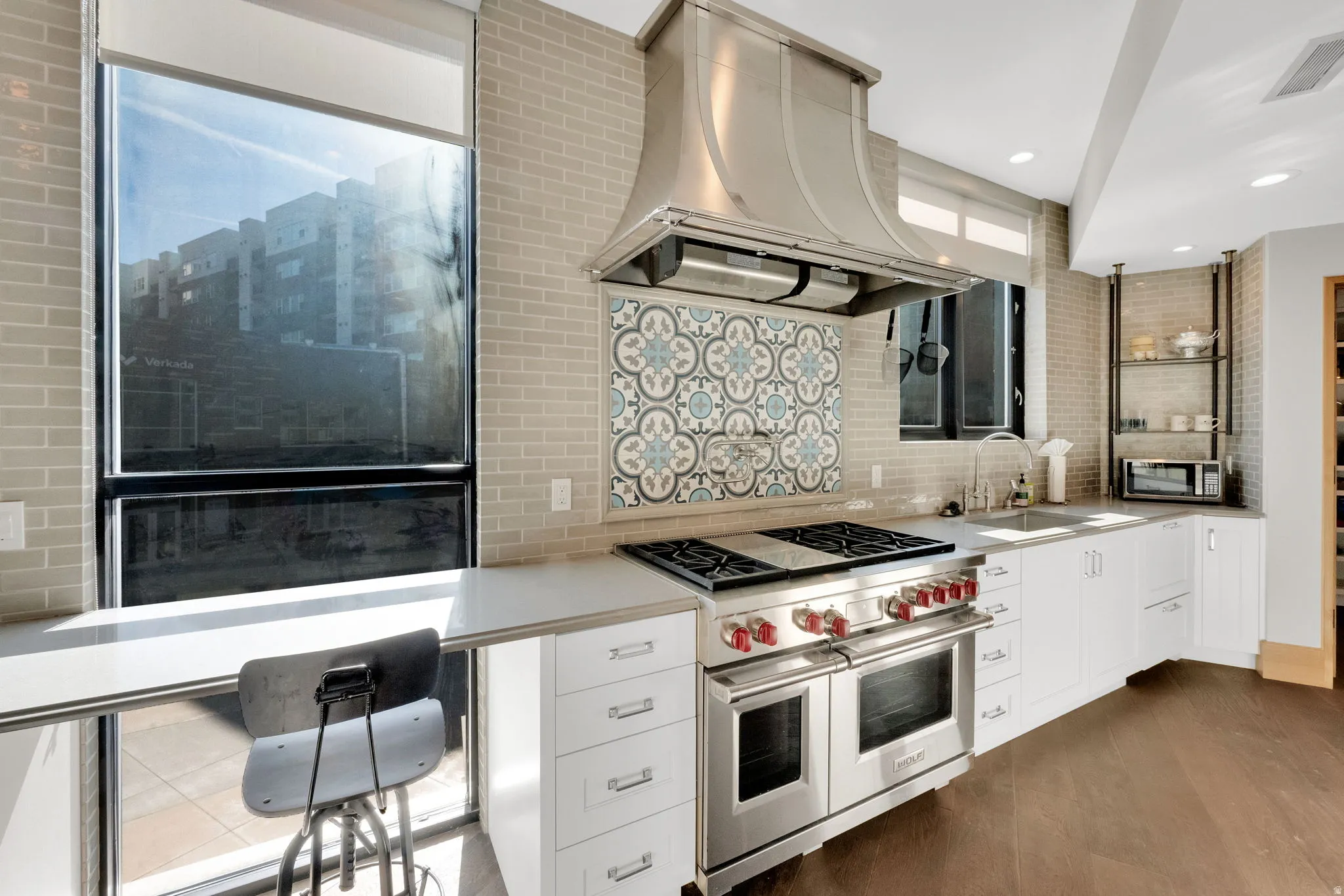 Kitchen featuring stainless steel appliances, white cabinetry, island range hood, light countertops, and dark wood finished floors