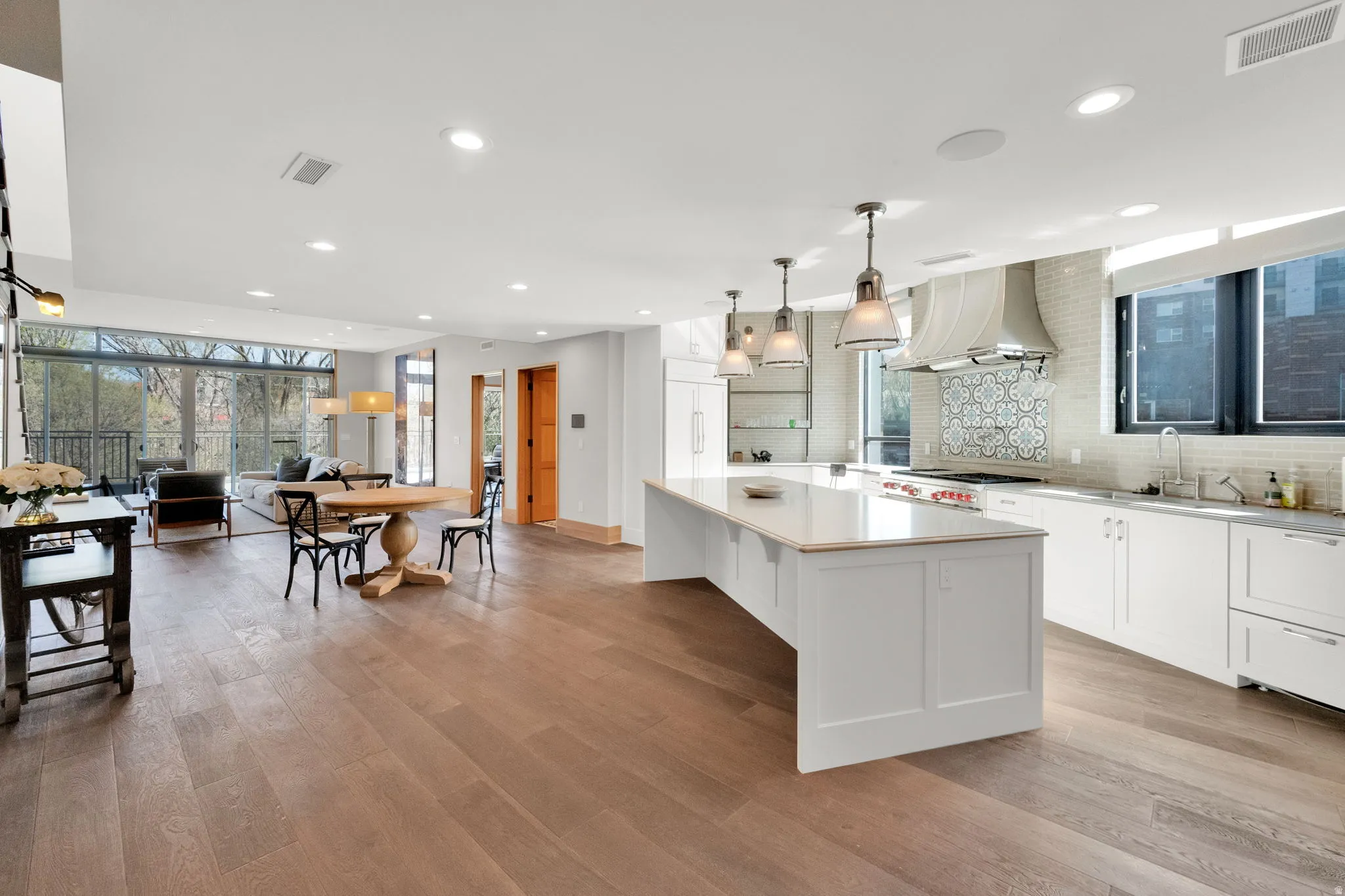Kitchen featuring white cabinetry, decorative backsplash, decorative light fixtures, a center island, and extractor fan