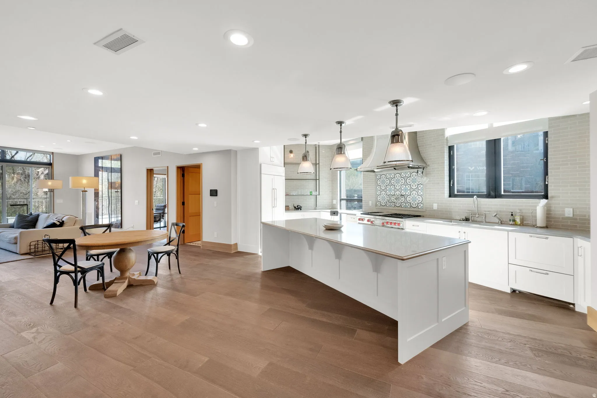 Kitchen featuring decorative backsplash, white cabinets, ventilation hood, a kitchen breakfast bar, and a large island