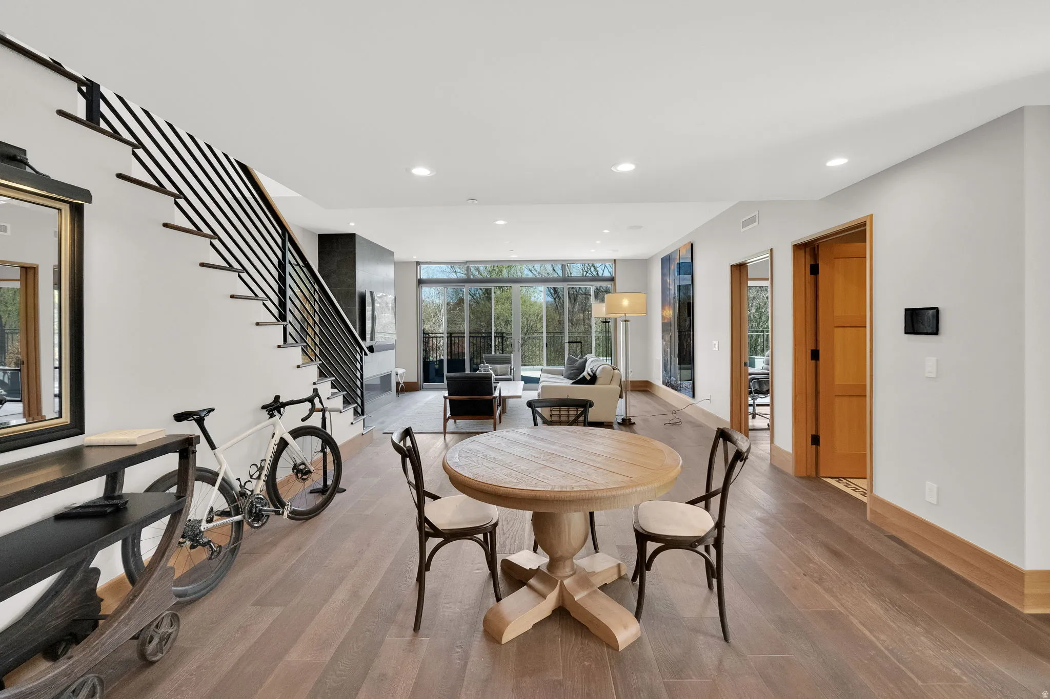 Dining room with light wood finished floors, floor to ceiling windows, and recessed lighting