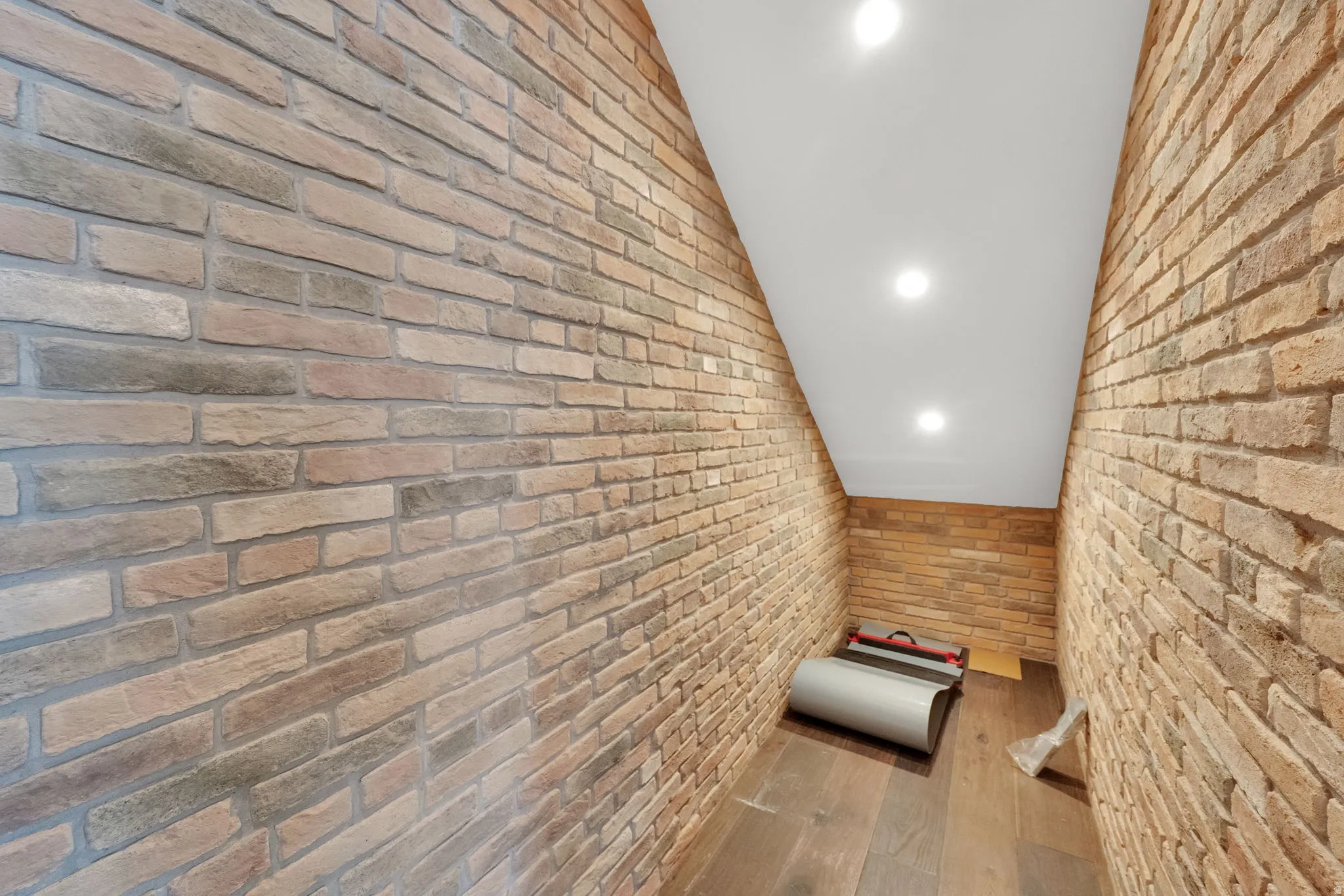 Corridor featuring lofted ceiling, brick wall, and recessed lighting