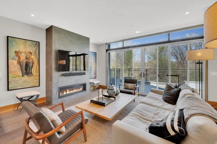 Living room with wood finished floors, a tile fireplace, and recessed lighting