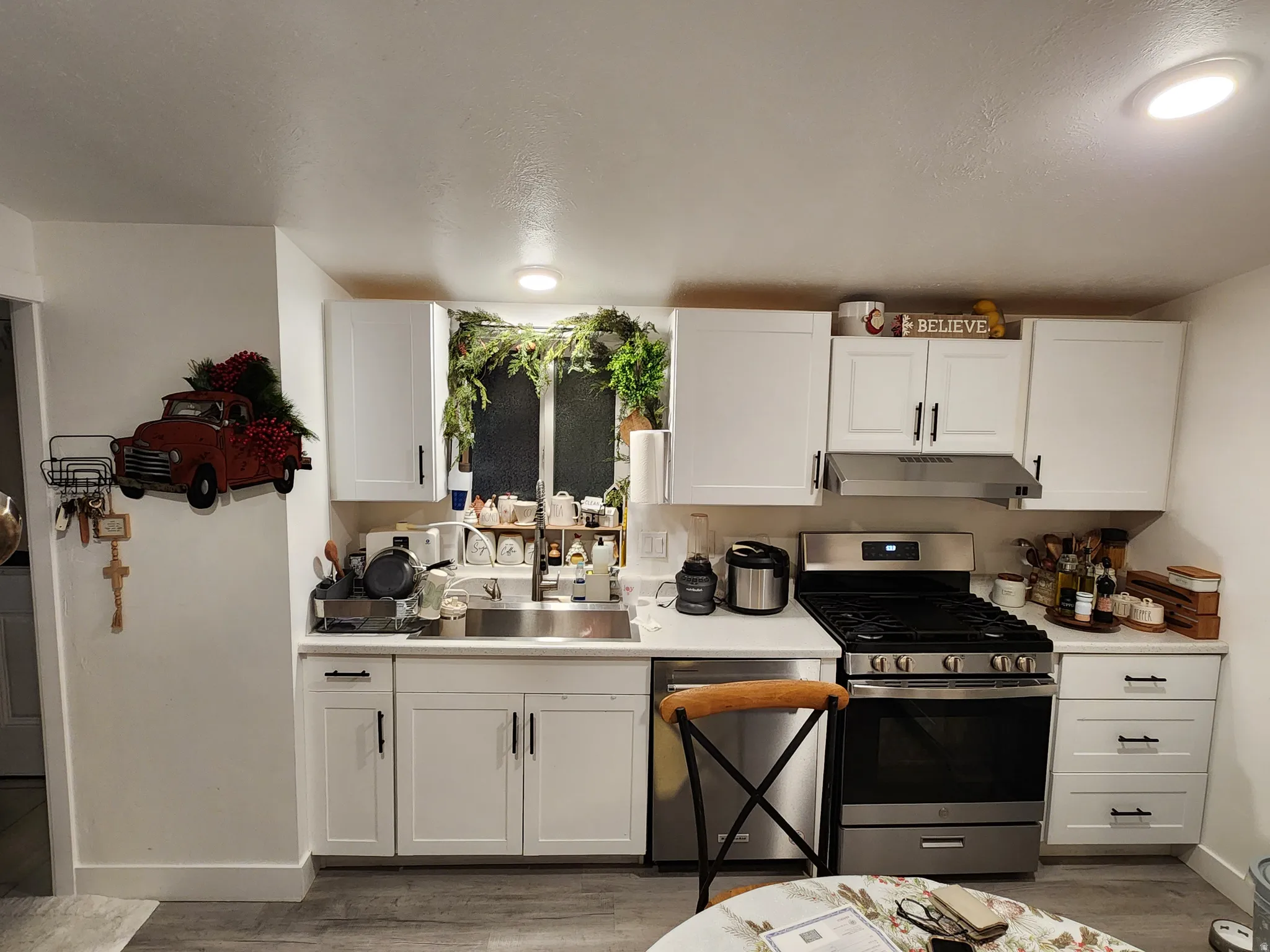 Kitchen with stainless steel appliances, light countertops, white cabinets, and light wood-type flooring