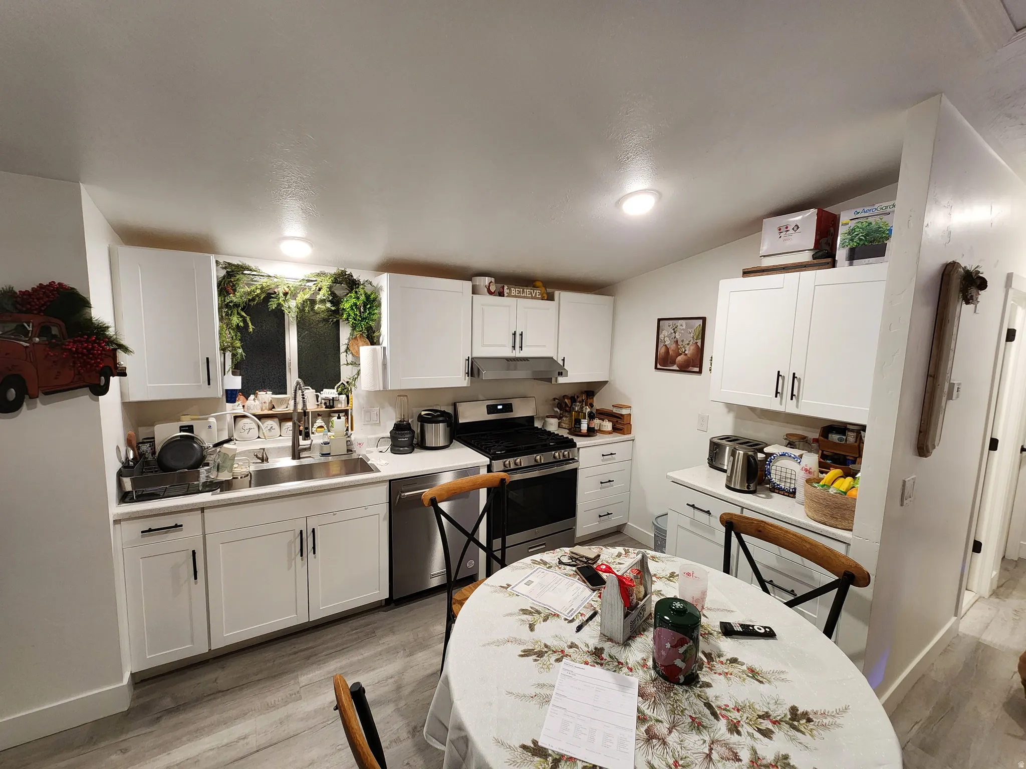 Kitchen featuring white cabinetry, stainless steel appliances, light countertops, light wood-style floors, and vaulted ceiling