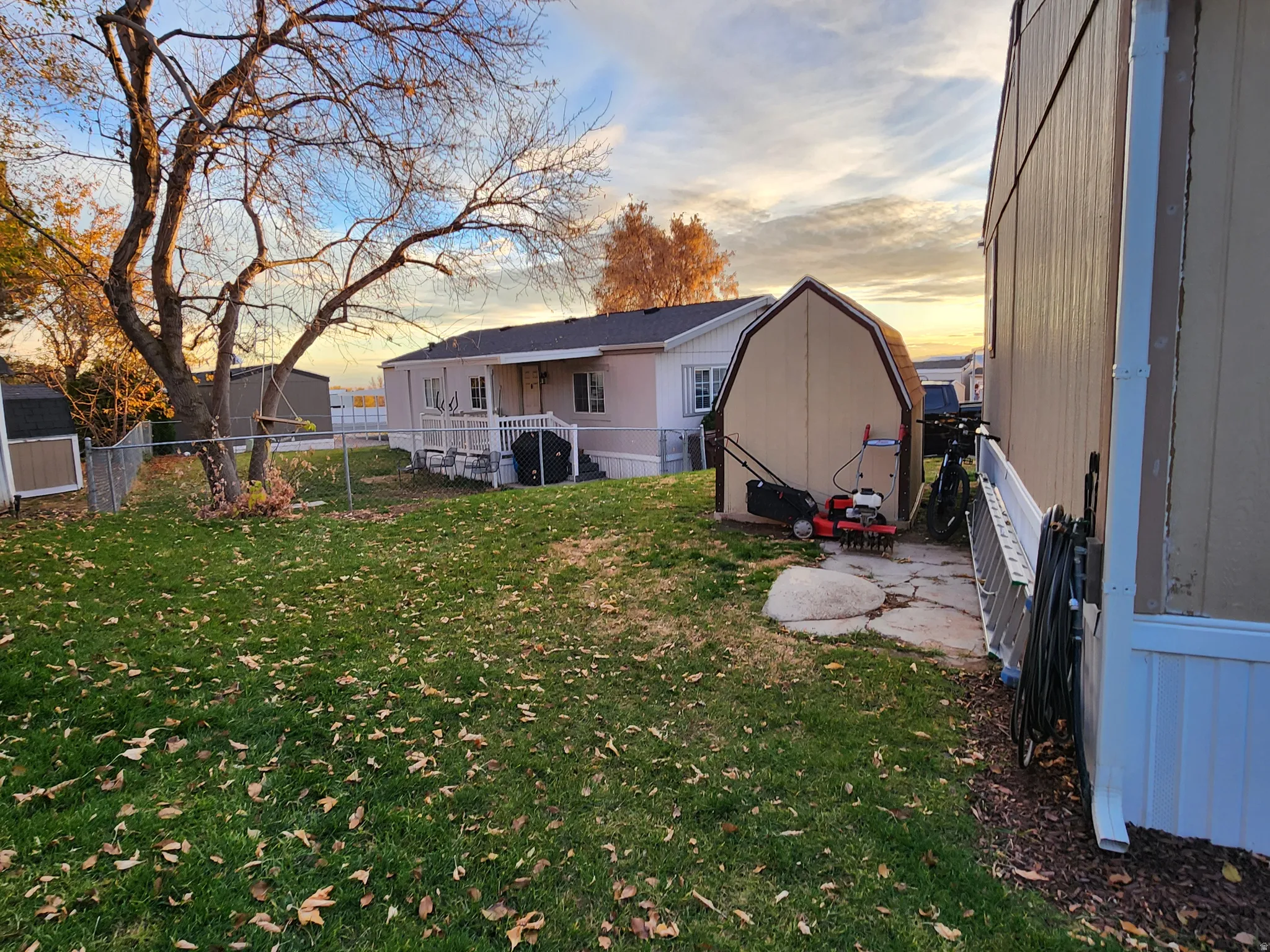 Back of house at dusk featuring a fenced backyard and a shed