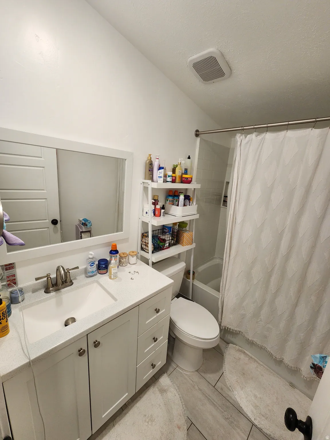 Full bath featuring vanity, shower / bath combo, light tile patterned flooring, and lofted ceiling