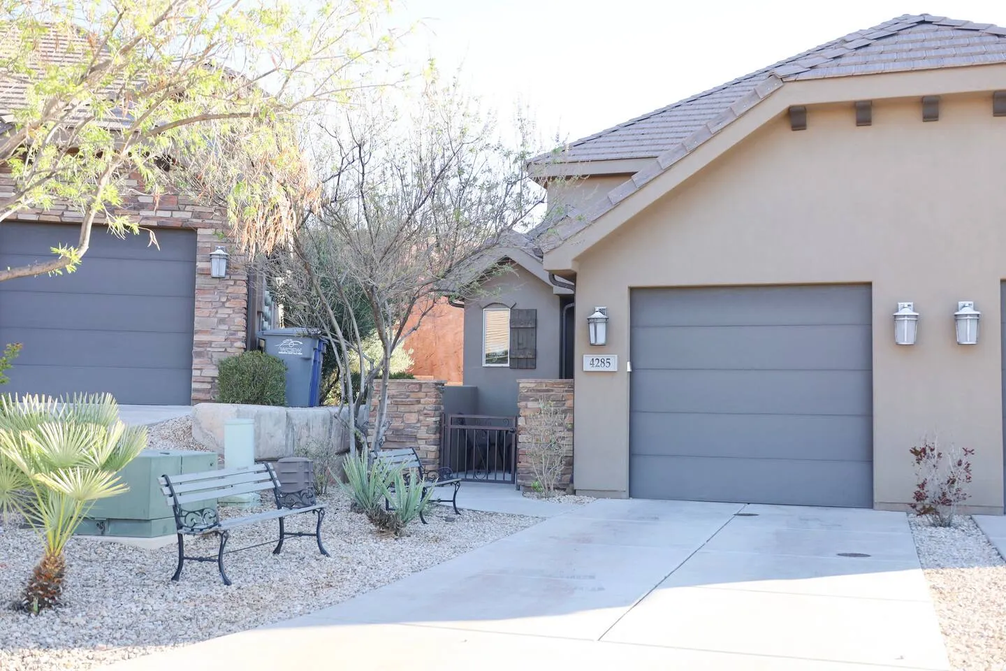 View of side of home featuring stone siding, concrete driveway, stucco siding, and a garage