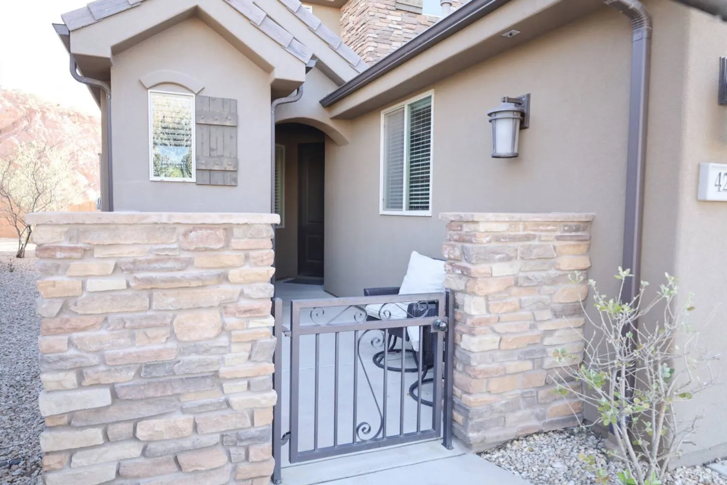 View of exterior entry with stone siding, stucco siding, and a gate