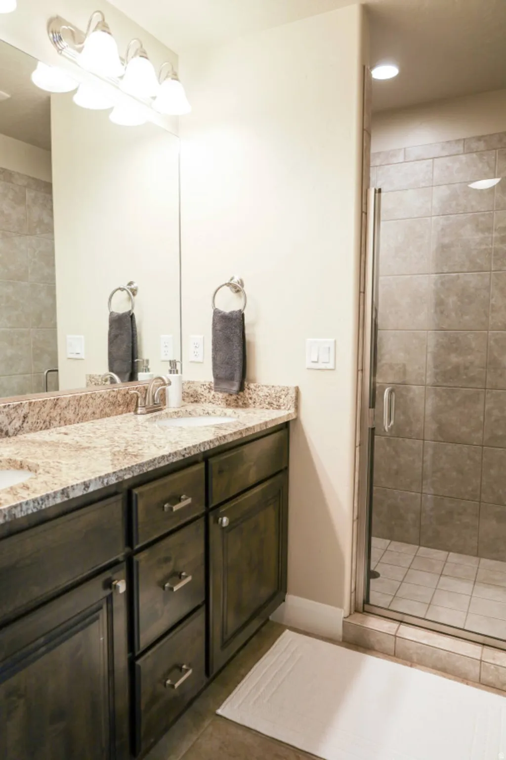 Full bathroom featuring double vanity, a stall shower, light tile patterned flooring, and recessed lighting