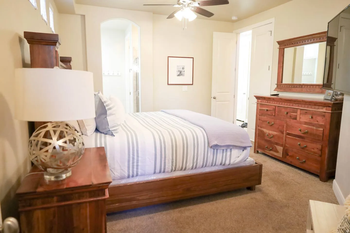 Bedroom featuring light colored carpet, a ceiling fan, and arched walkways