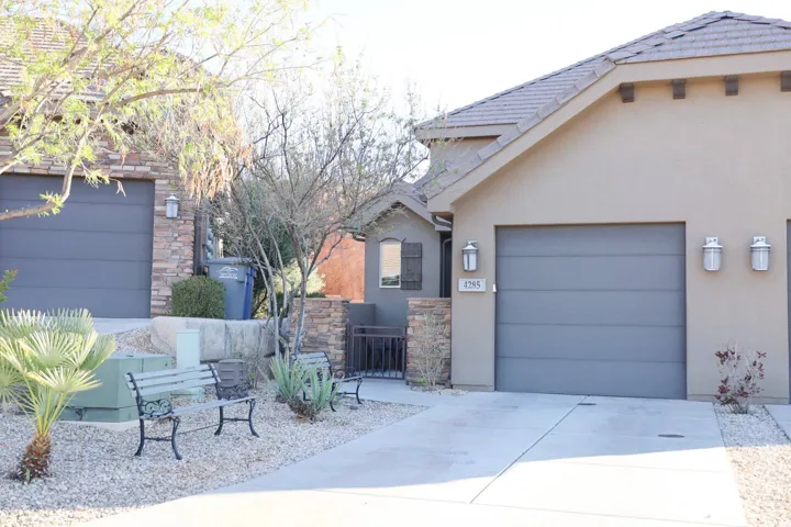 View of side of home featuring stone siding, concrete driveway, stucco siding, and a garage