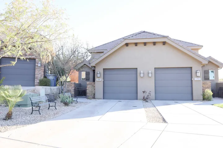 View of front facade with an attached garage, stucco siding, concrete driveway, and stone siding