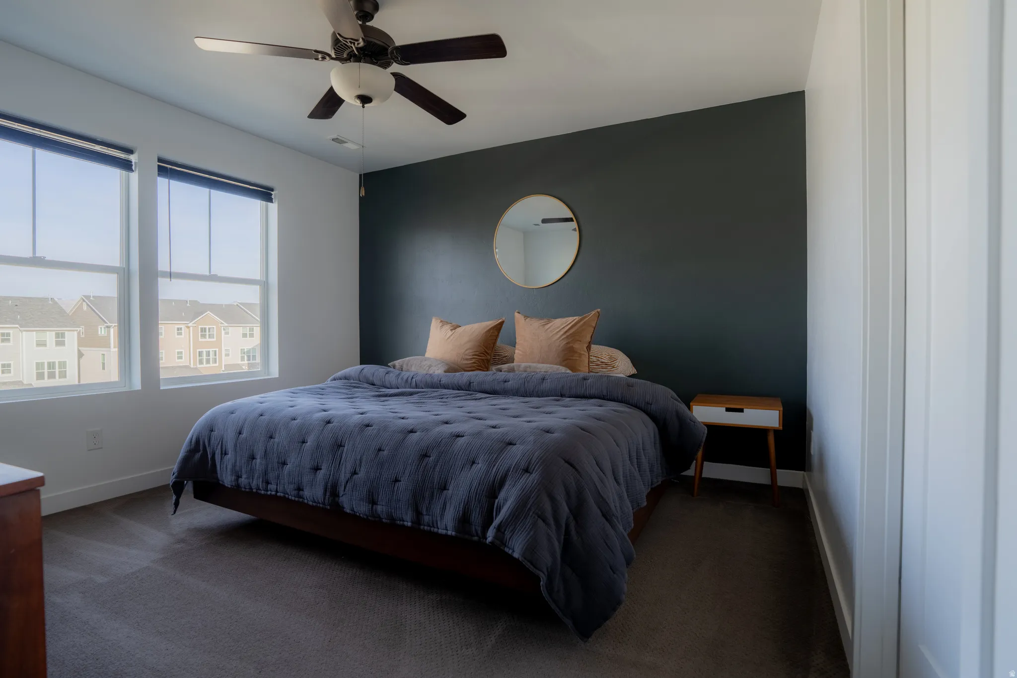 Carpeted bedroom featuring a ceiling fan and an accent wall