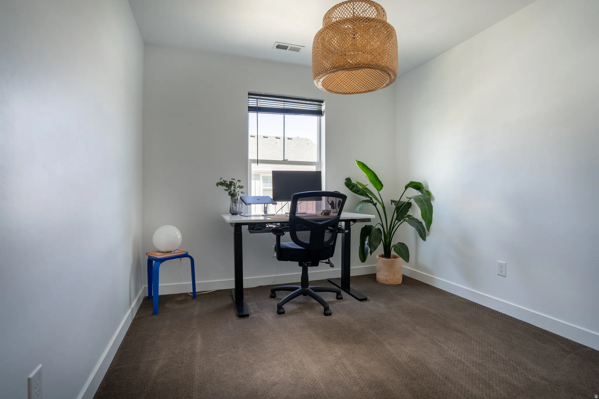 Office with dark colored carpet and baseboards
