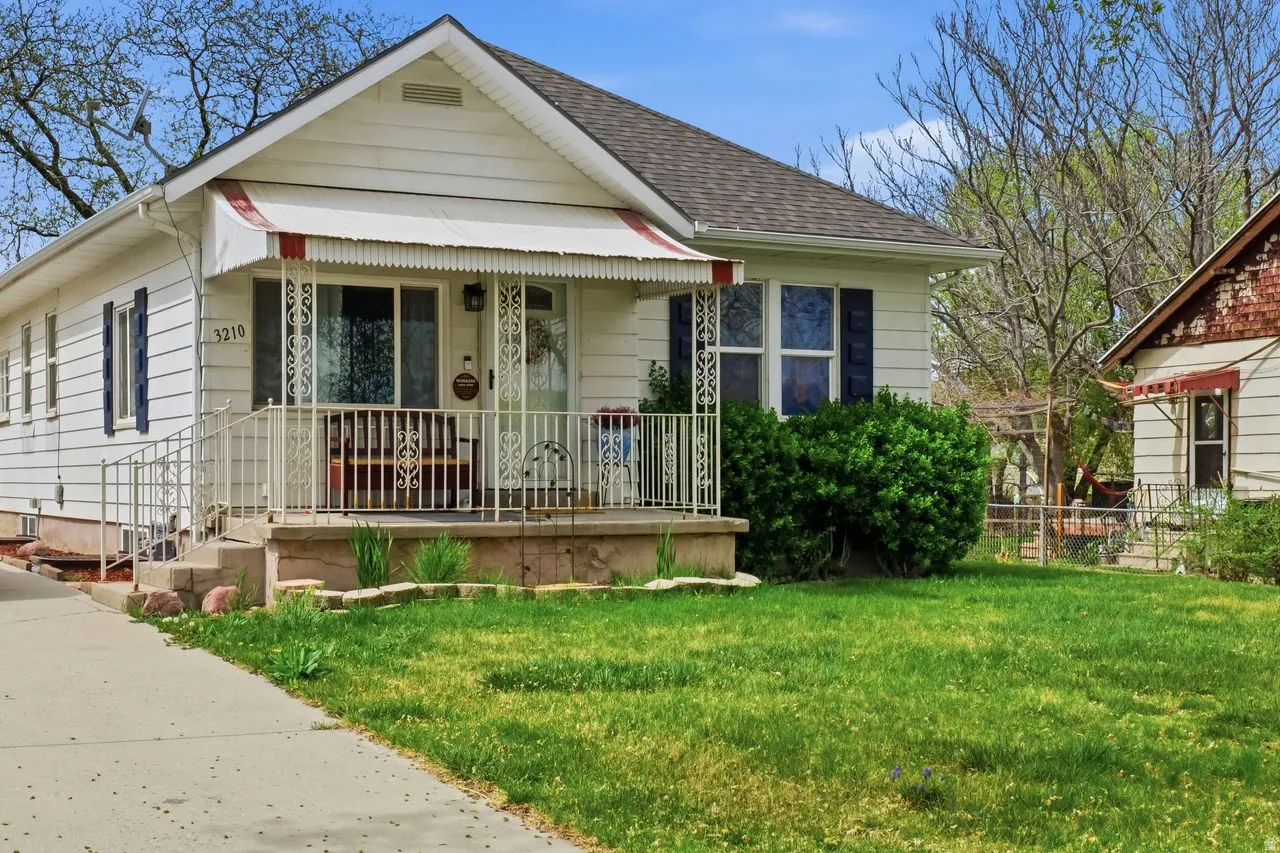 Bungalow-style home featuring covered porch, a front lawn, and a shingled roof