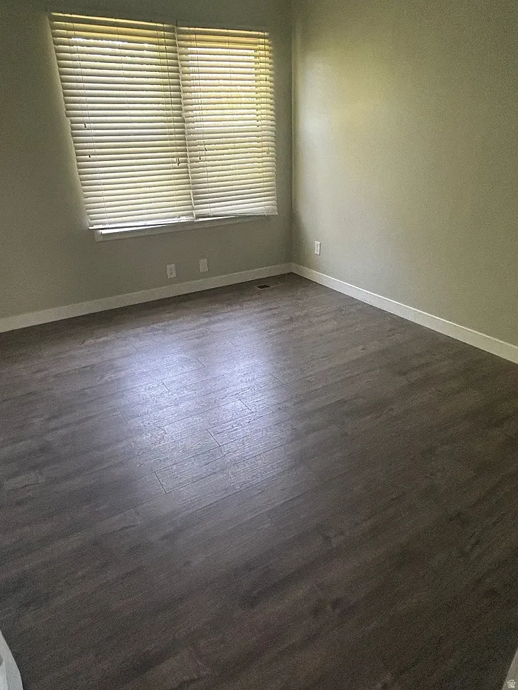 Unfurnished room featuring baseboards and dark wood-type flooring