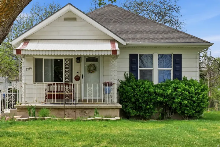 Bungalow-style home with covered porch, a front lawn, and roof with shingles
