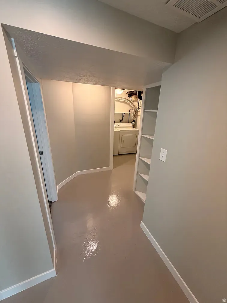 Corridor featuring concrete flooring and washing machine and clothes dryer