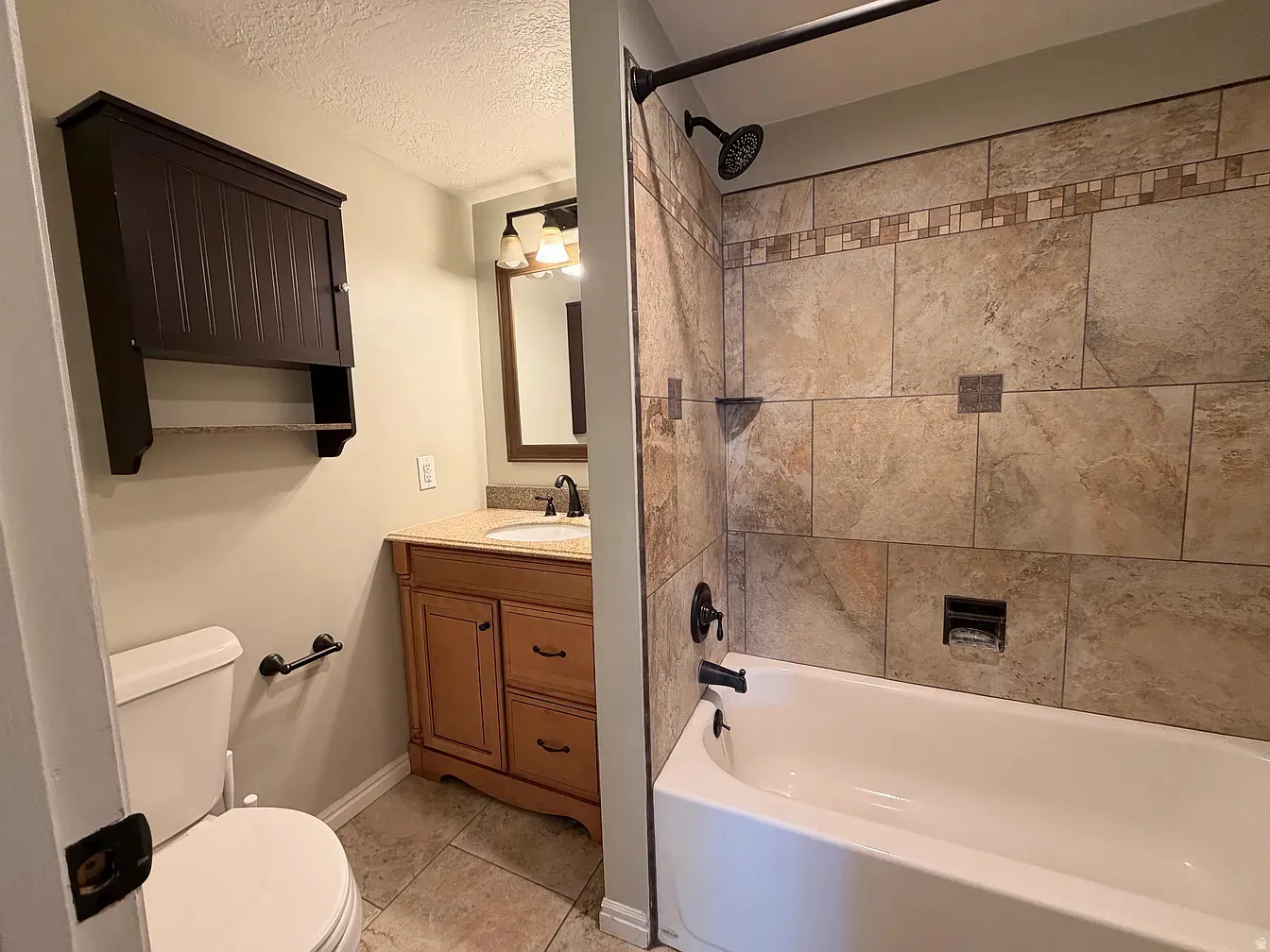 Bathroom with vanity, a textured ceiling, bathtub / shower combination, and light tile patterned flooring