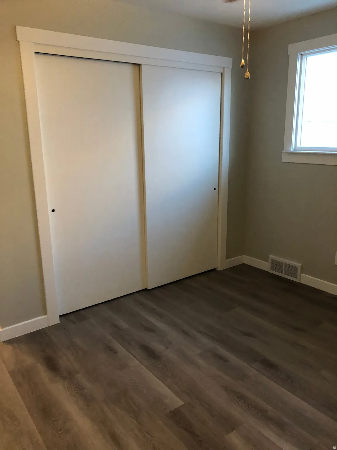 Unfurnished bedroom featuring dark wood-style floors, a closet, and ceiling fan
