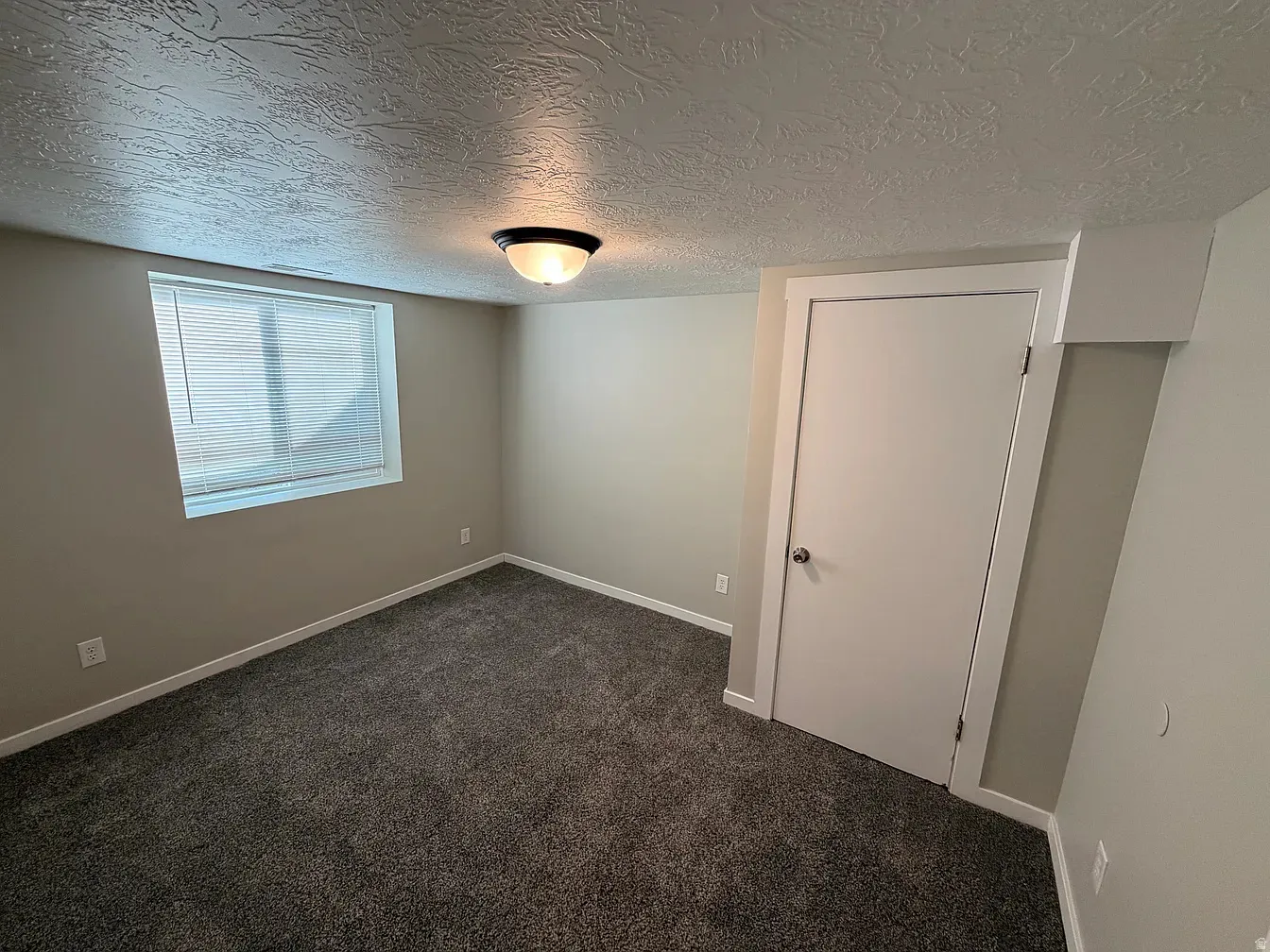 Unfurnished bedroom featuring a textured ceiling and dark carpet