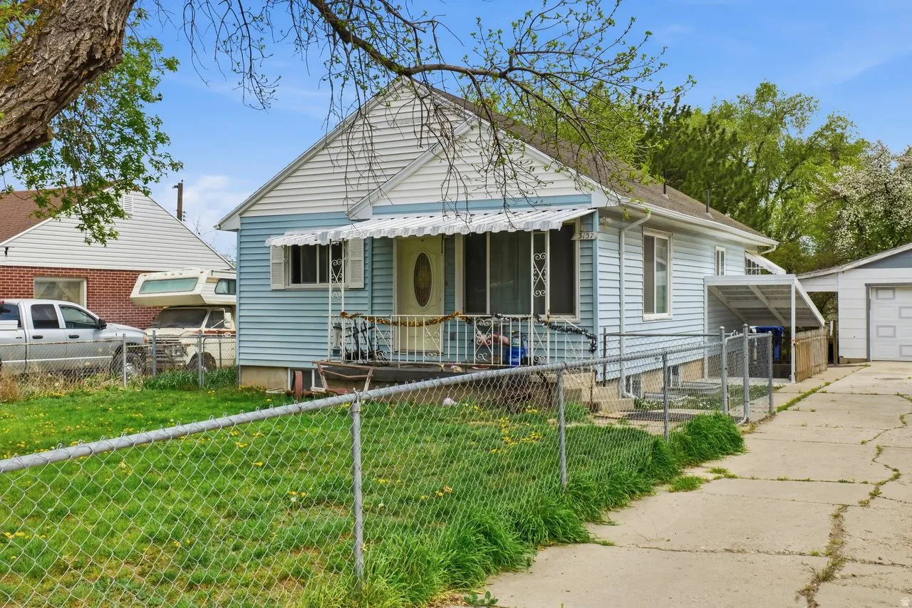 Bungalow-style home with an outdoor structure, a fenced front yard, and a garage