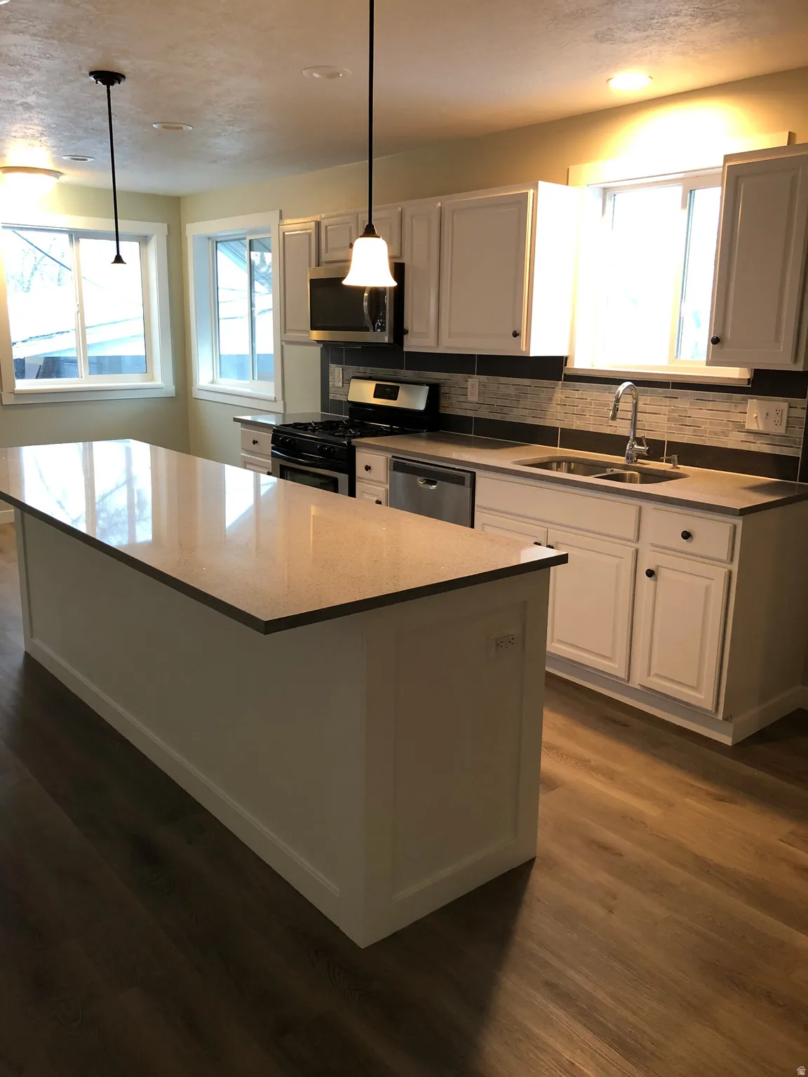 Kitchen with stainless steel appliances, pendant lighting, a kitchen island, and white cabinets