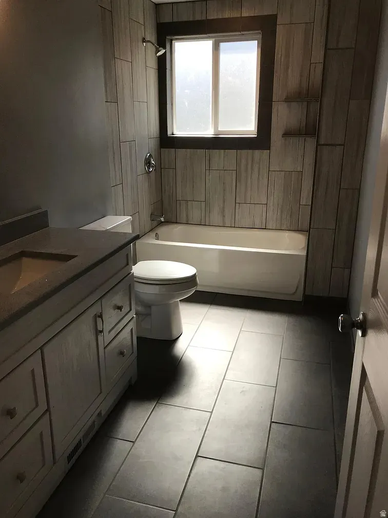 Bathroom with vanity, shower / bath combination, and light tile patterned floors