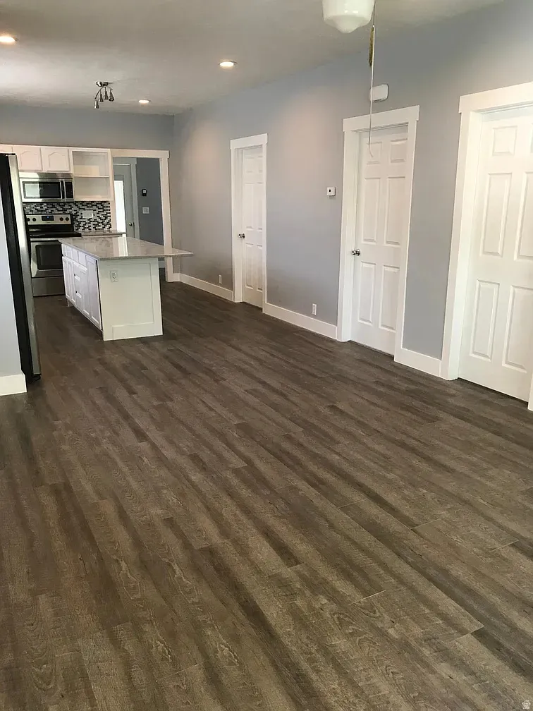 Kitchen with white cabinets, dark wood-type flooring, stainless steel appliances, backsplash, and a kitchen island