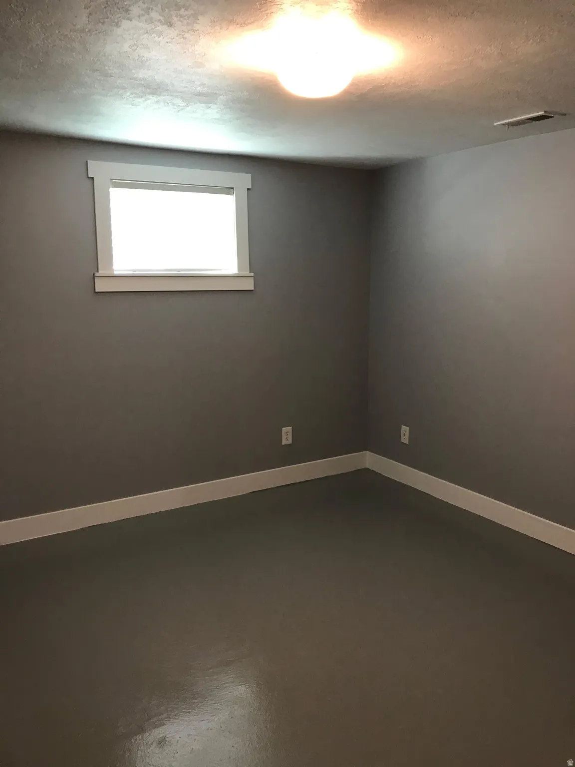 Spare room featuring a textured ceiling and concrete flooring