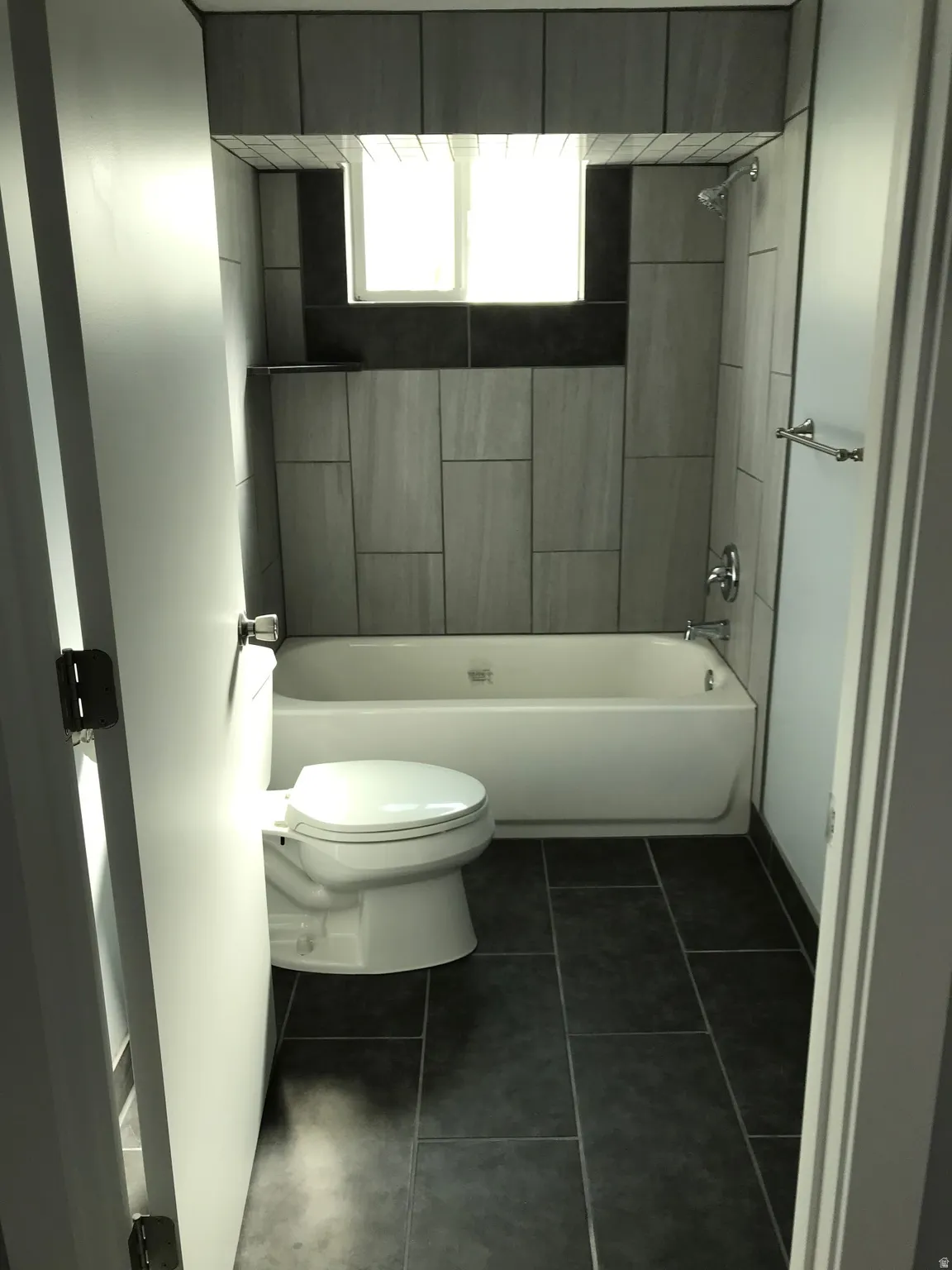Bathroom with dark tile patterned floors and shower / tub combination