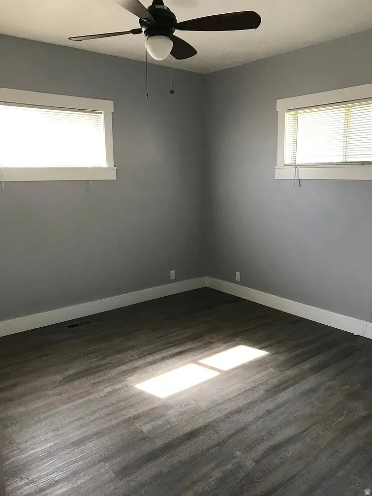 Spare room with a ceiling fan and dark wood-style flooring