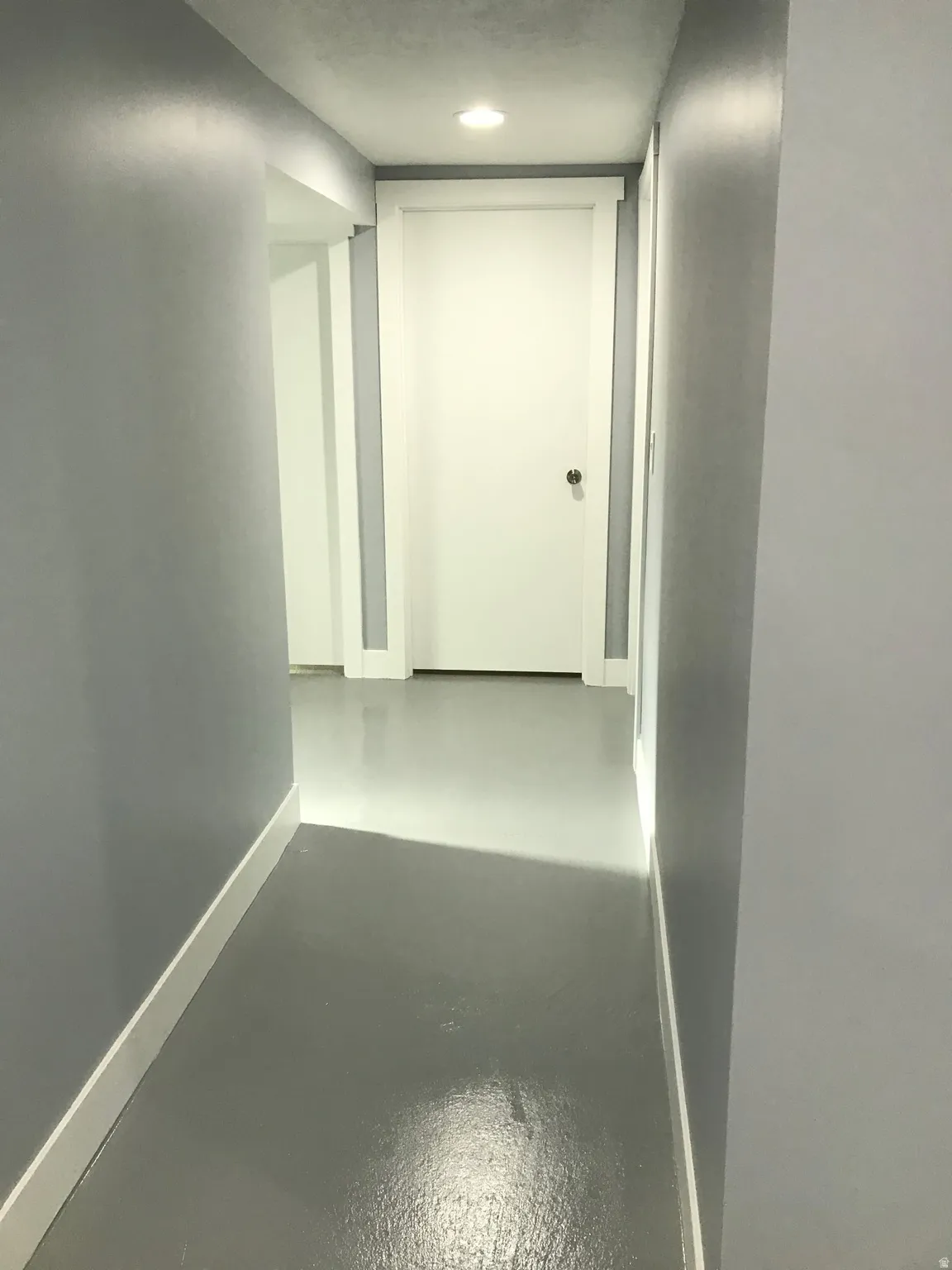 Corridor featuring baseboards and finished concrete flooring