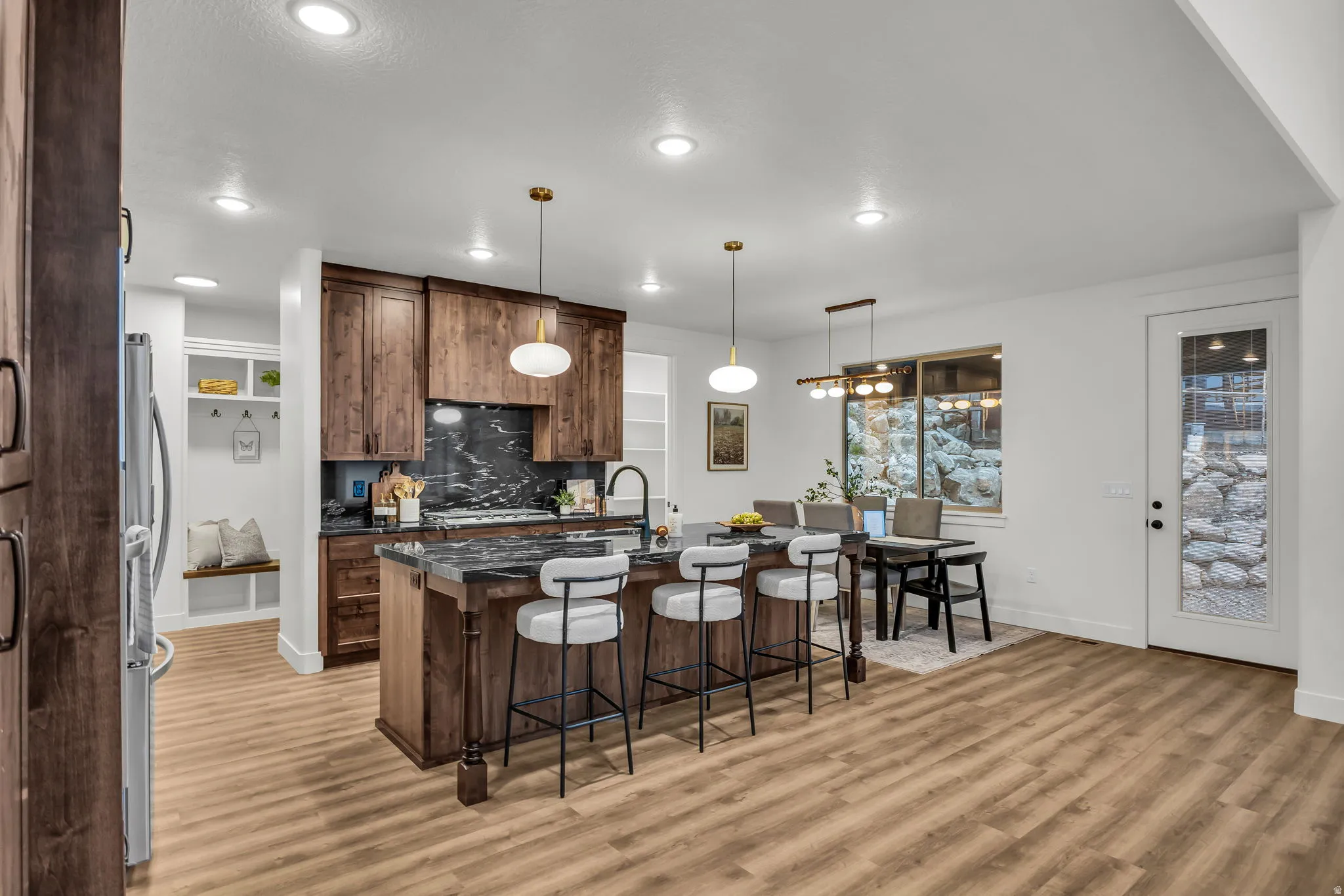 Kitchen with a kitchen breakfast bar, a center island with sink, dark stone countertops, decorative light fixtures, and decorative backsplash