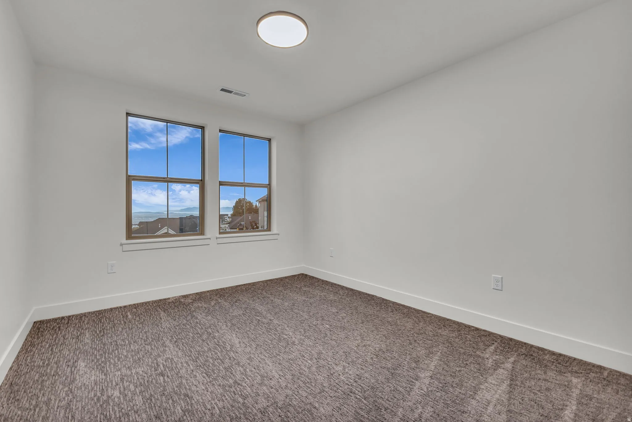 Empty room featuring baseboards and dark colored carpet