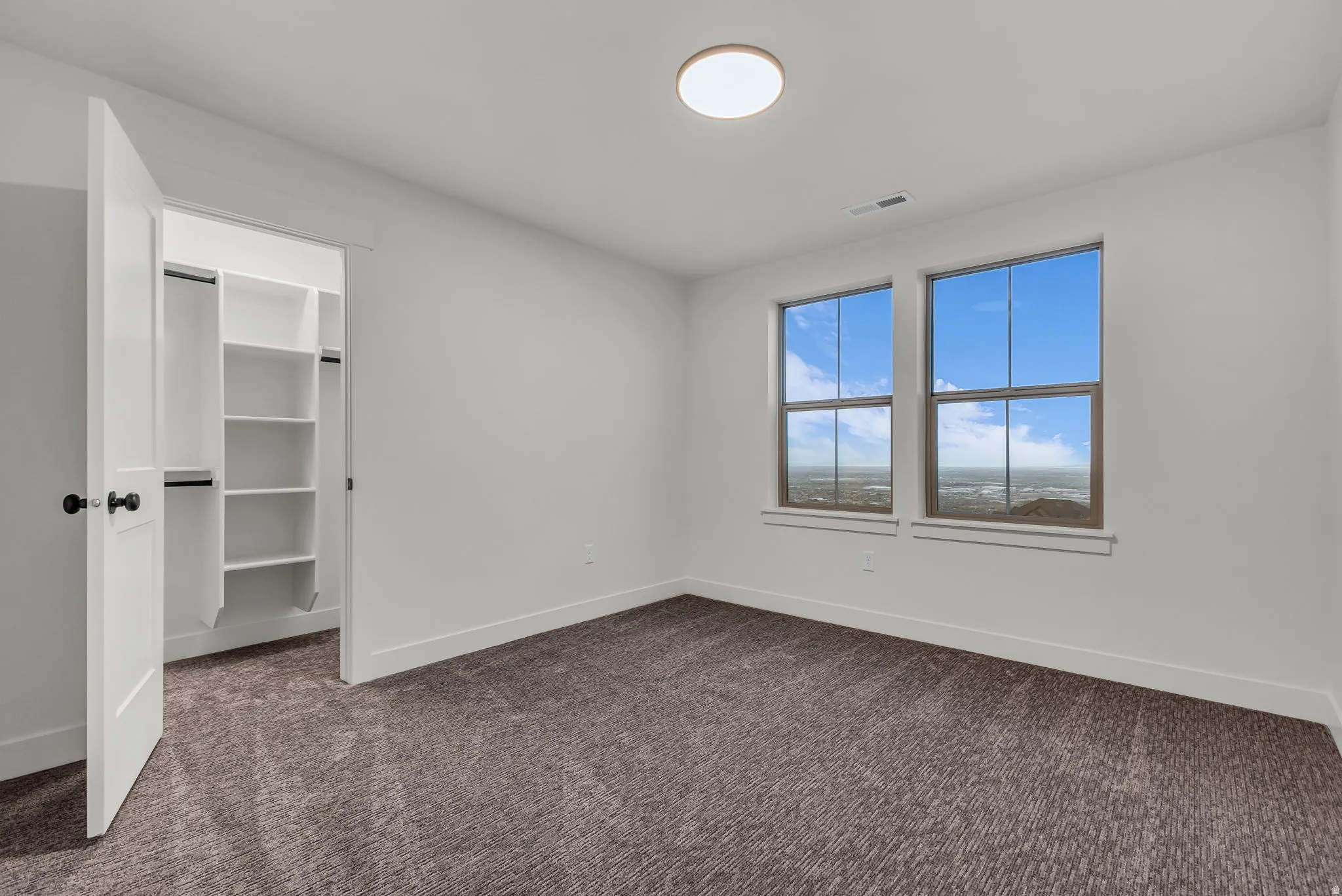 Unfurnished bedroom with a walk in closet and dark colored carpet