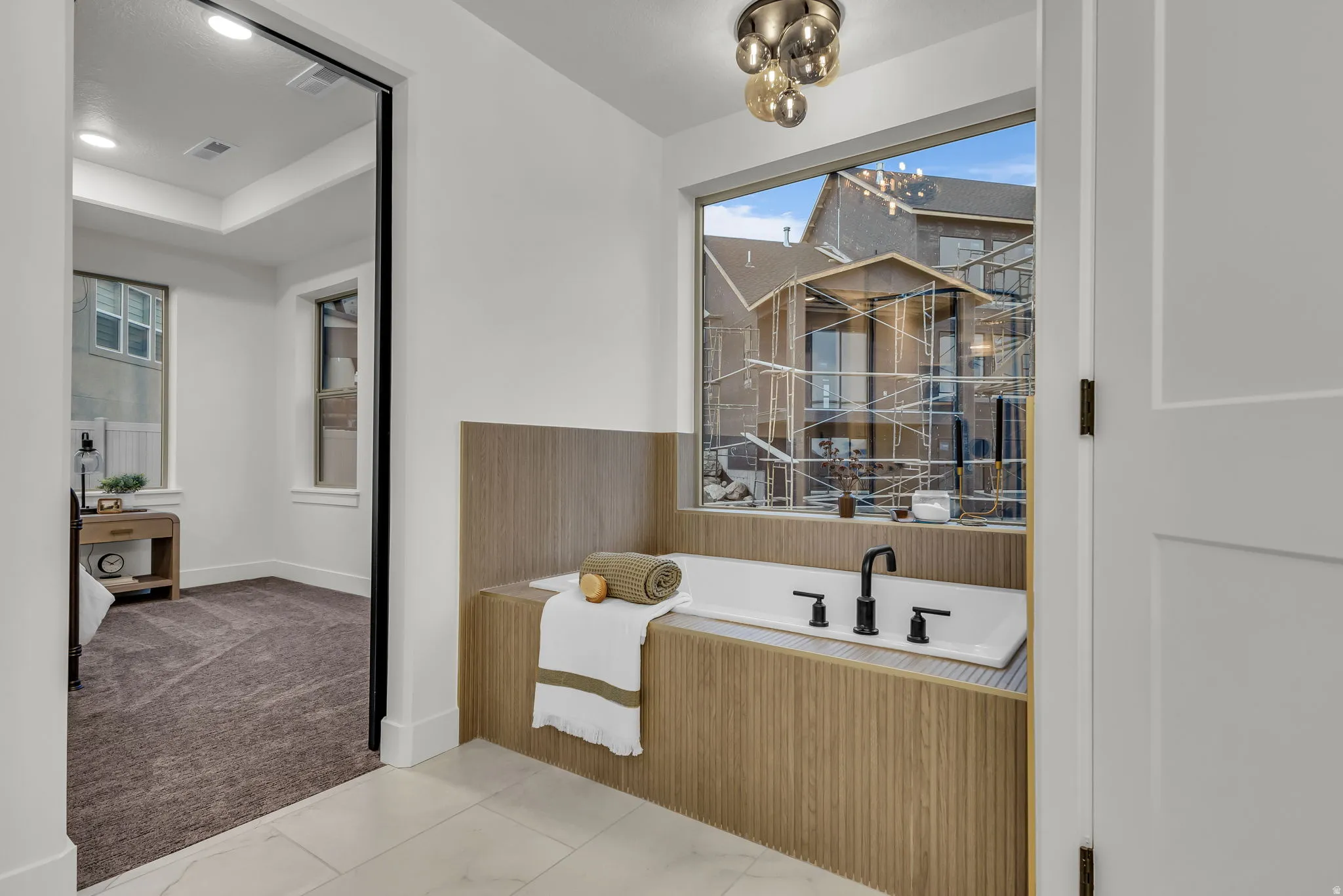 Full bathroom featuring a bath, light carpet, and a tray ceiling