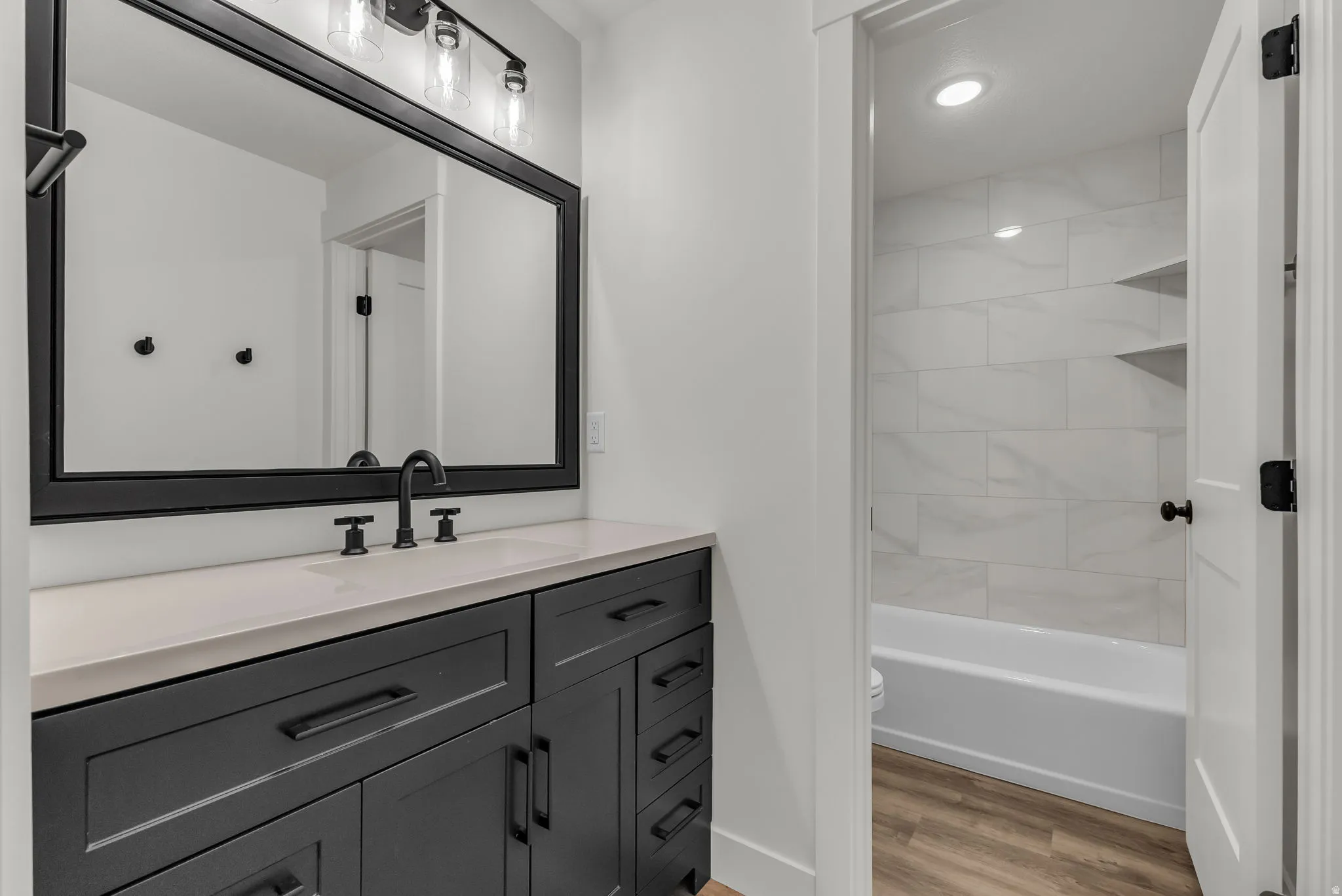 Bathroom featuring vanity, light wood-style flooring, recessed lighting, and bathtub / shower combination