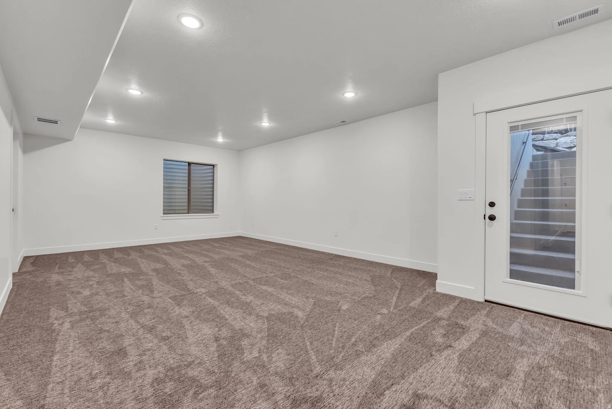 Empty room with recessed lighting and dark carpet