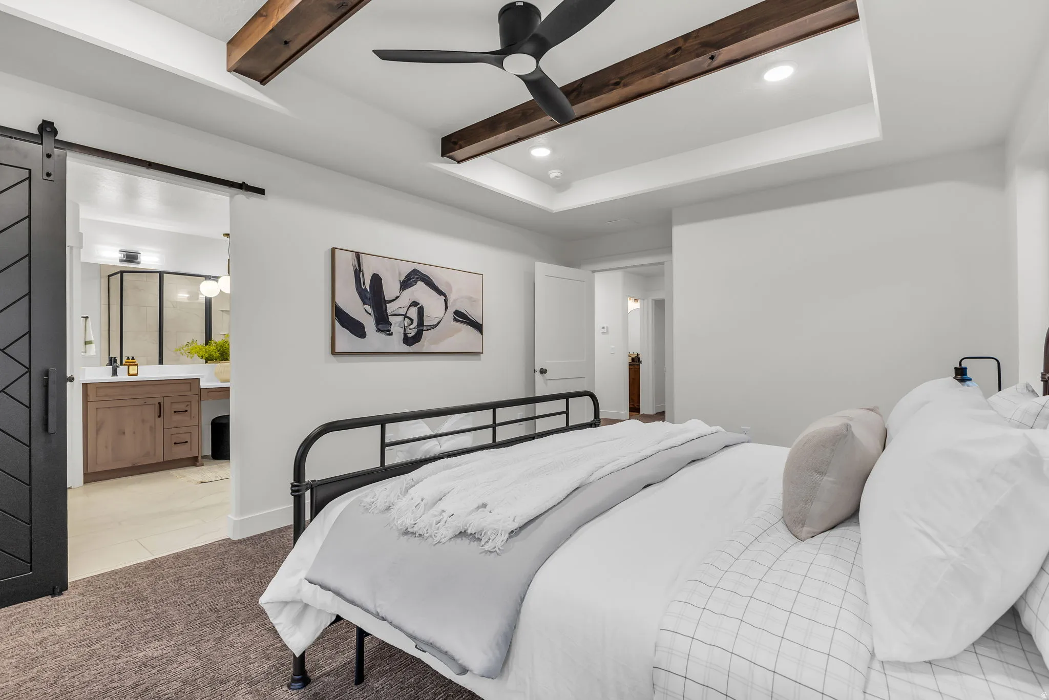 Carpeted bedroom featuring a barn door, recessed lighting, ensuite bath, a ceiling fan, and beam ceiling