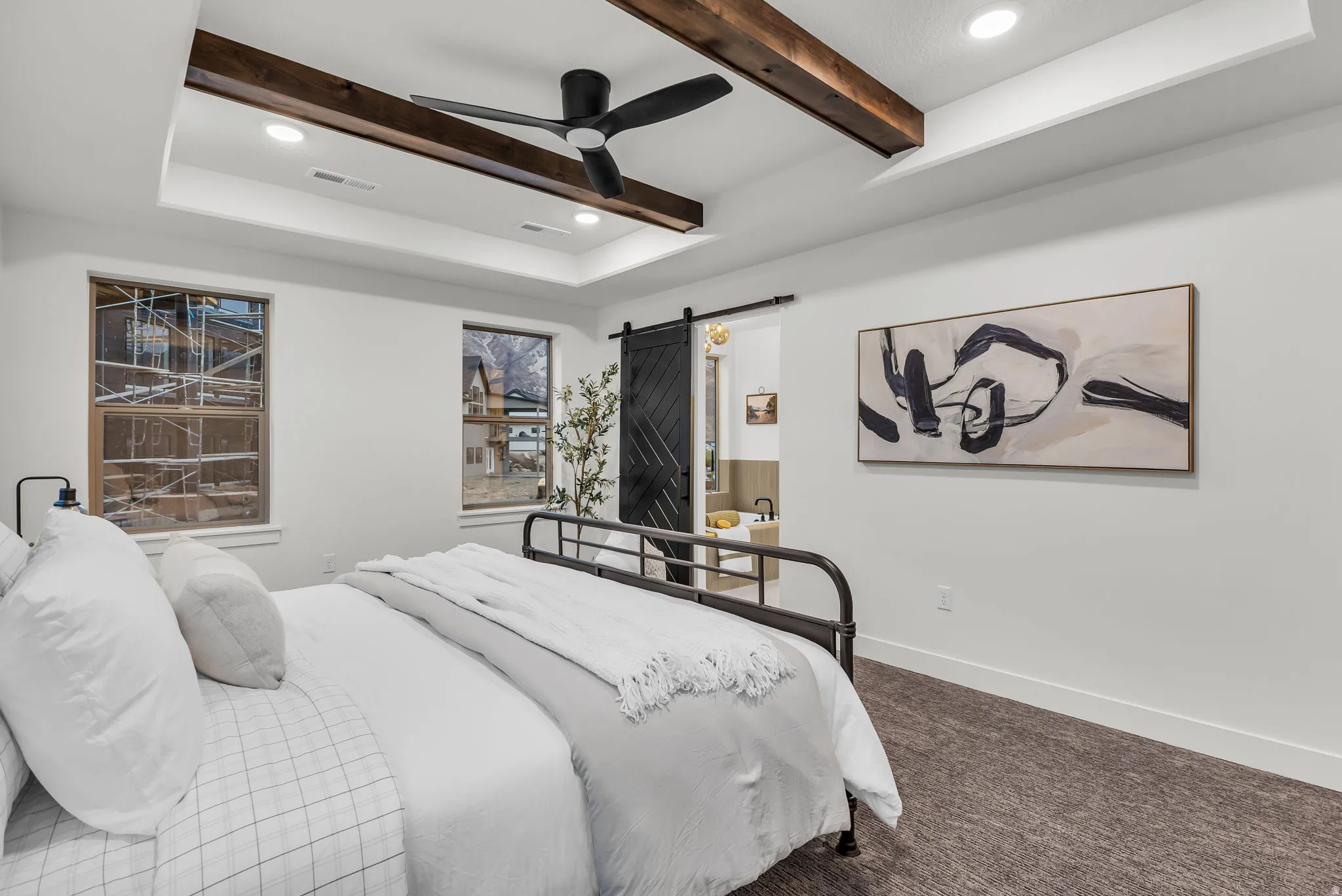 Carpeted bedroom with recessed lighting, a barn door, a ceiling fan, a raised ceiling, and connected bathroom