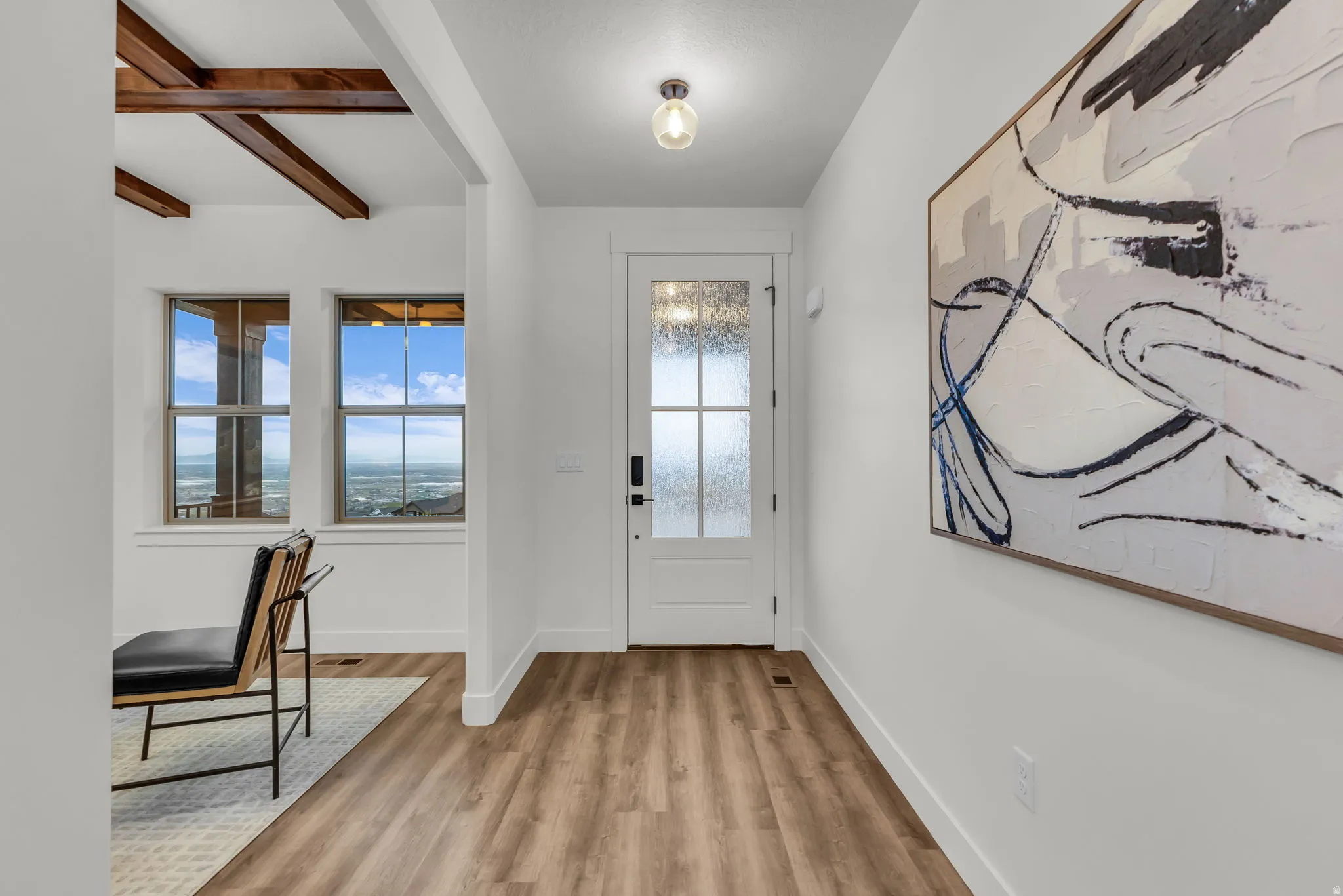 Entrance foyer with beamed ceiling and light wood-style flooring