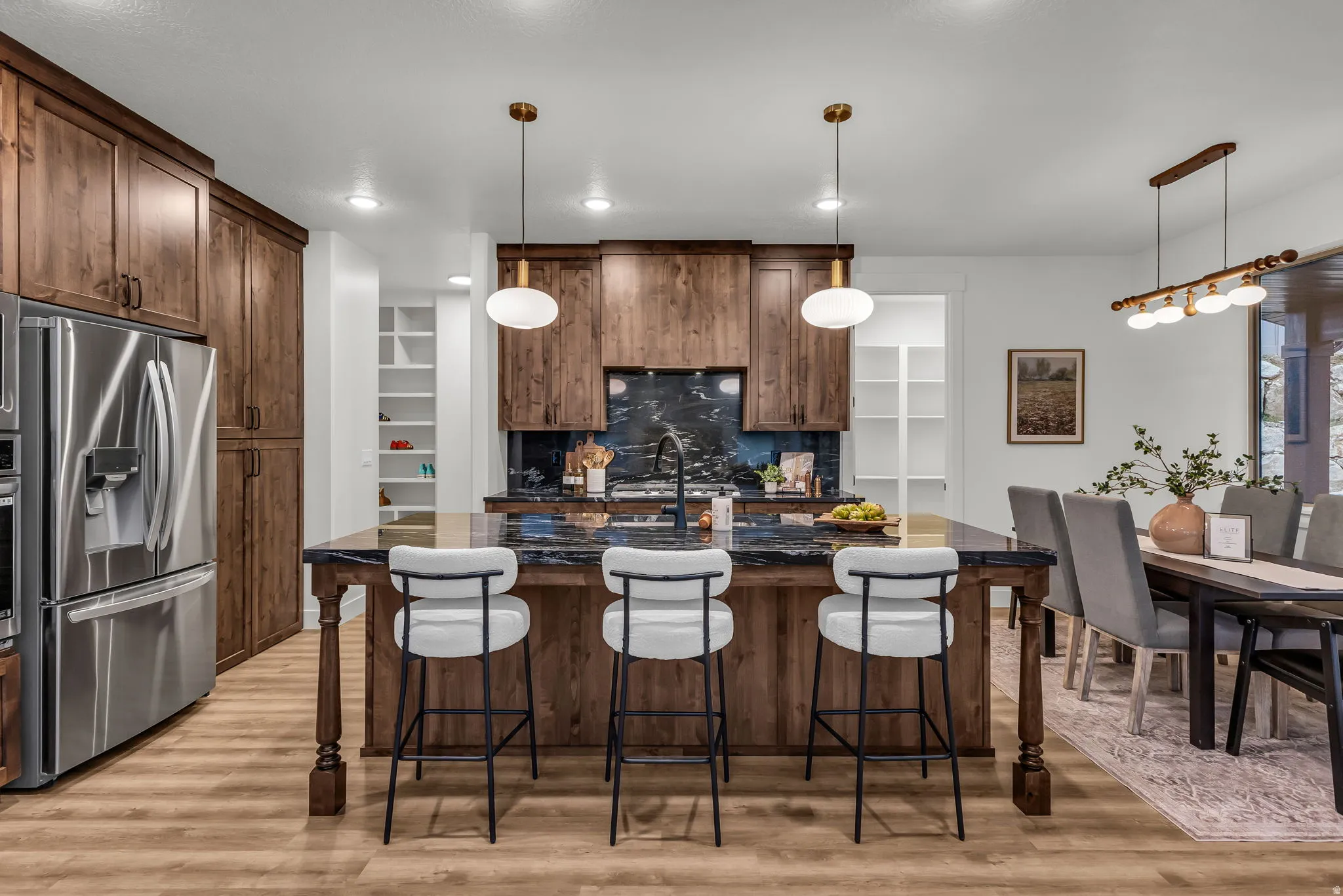Kitchen with a kitchen bar, a center island with sink, stainless steel refrigerator with ice dispenser, and light wood-style flooring