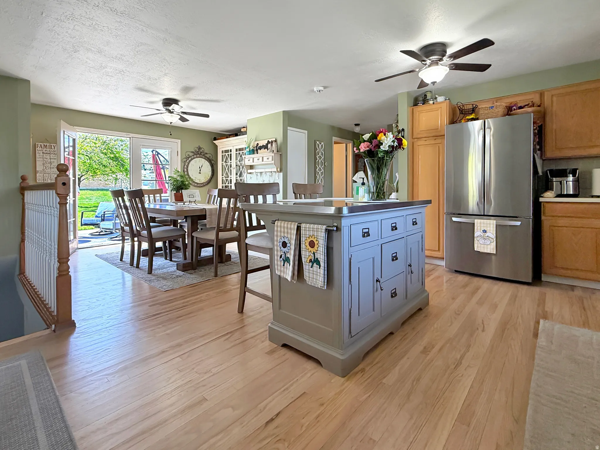 Kitchen with ceiling fan, freestanding refrigerator, light wood-style floors, a center island, and a textured ceiling