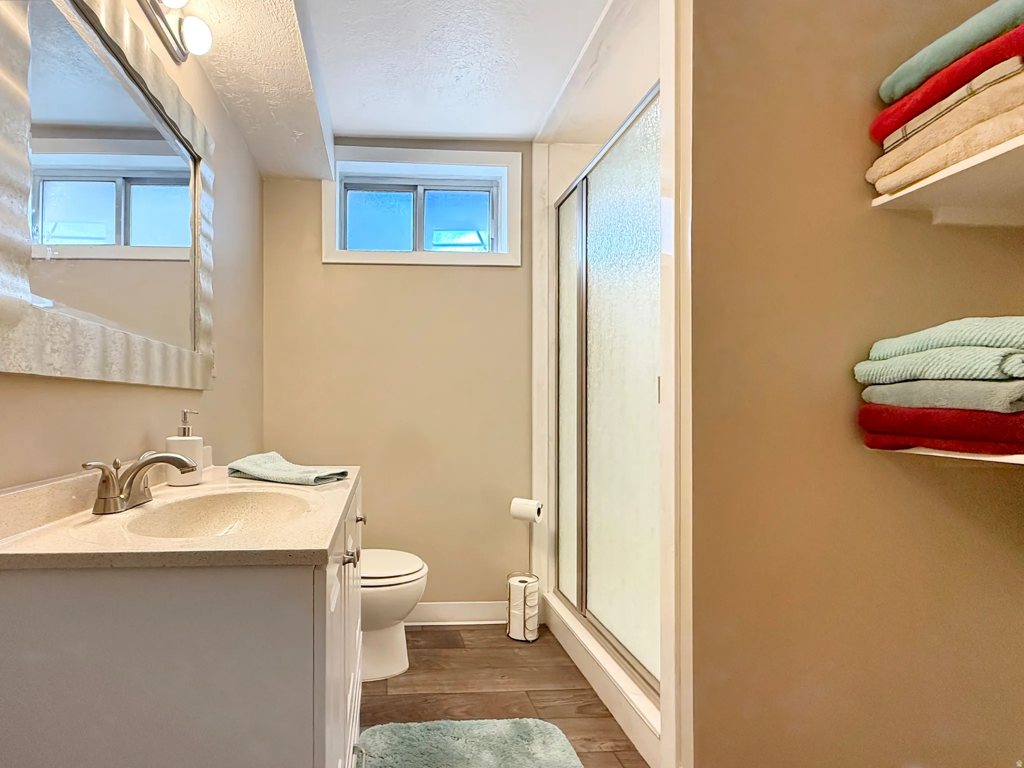 Full bath featuring vanity, a shower stall, dark wood-type flooring, and a textured ceiling