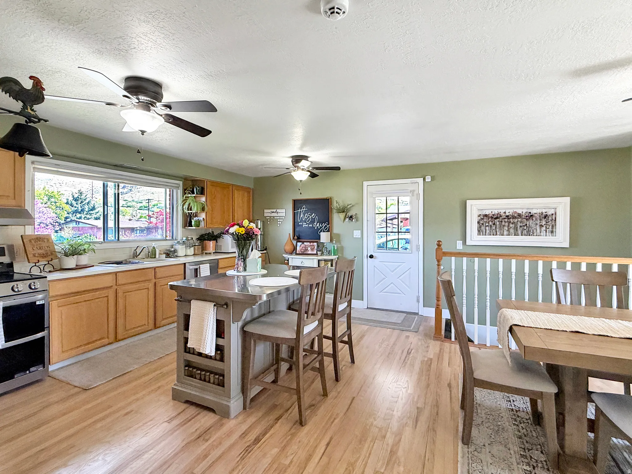 Kitchen with stainless steel appliances, light countertops, light wood-type flooring, a textured ceiling, and light wood finish cabinetry
